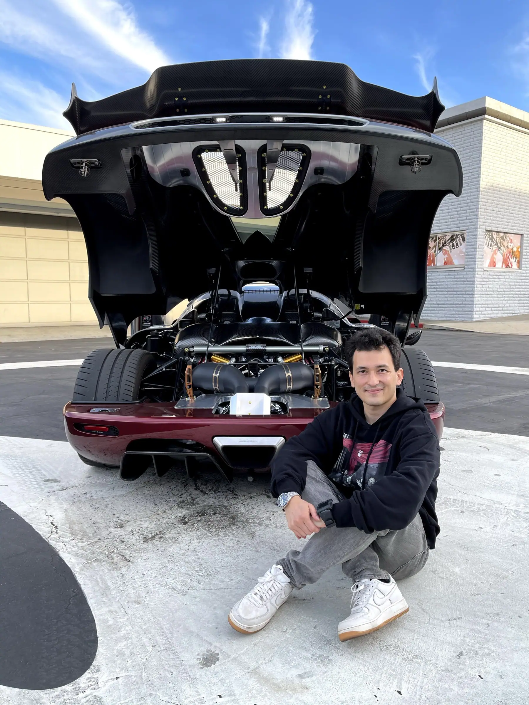 Alan in front of a hypercar with its rear engine cover open