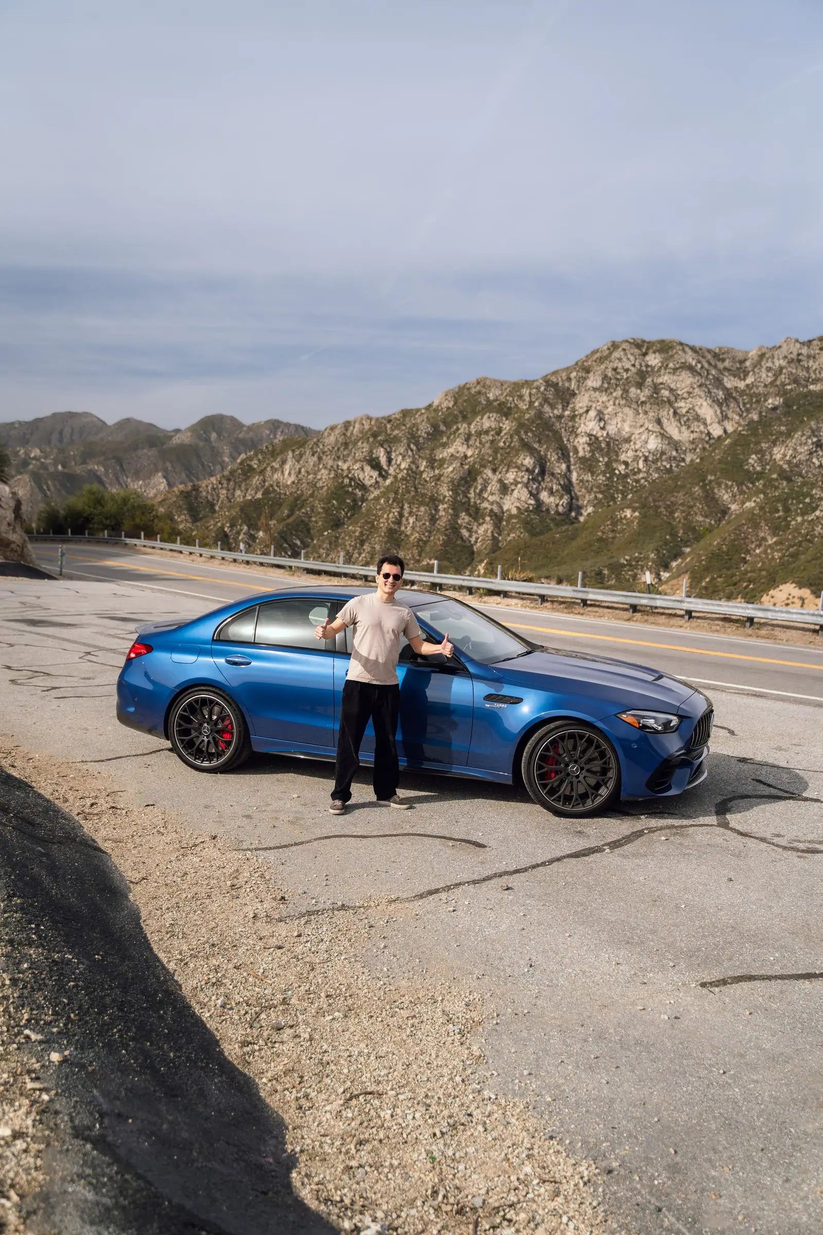 Blue Mercedes-AMG C 63 on a mountain road with Alan beside it